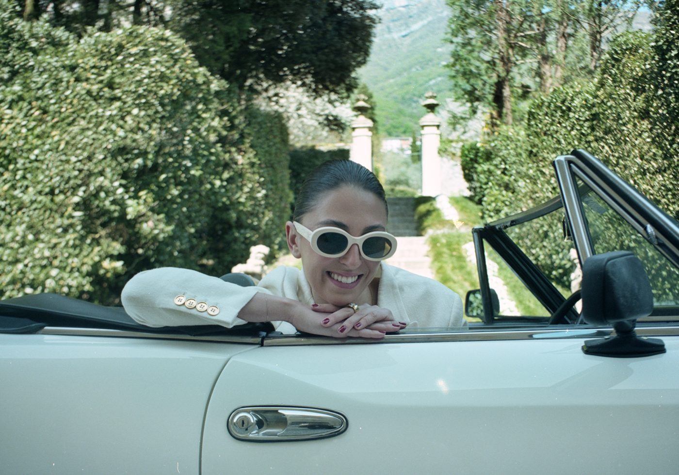 Guest in white sunglasses leaning on a vintage convertible