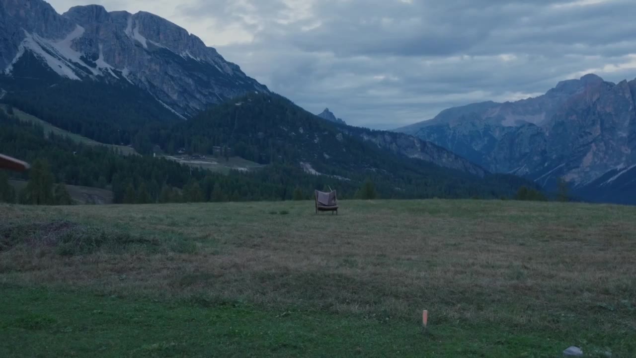 Still from the winter campaign film: carrying a chair across a Dolomites meadow